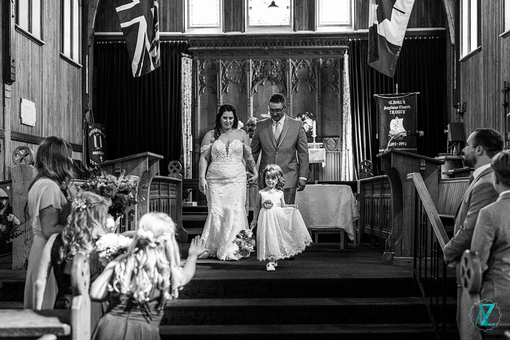 Black and white photo of a wedding party exiting down church steps after ceremony.