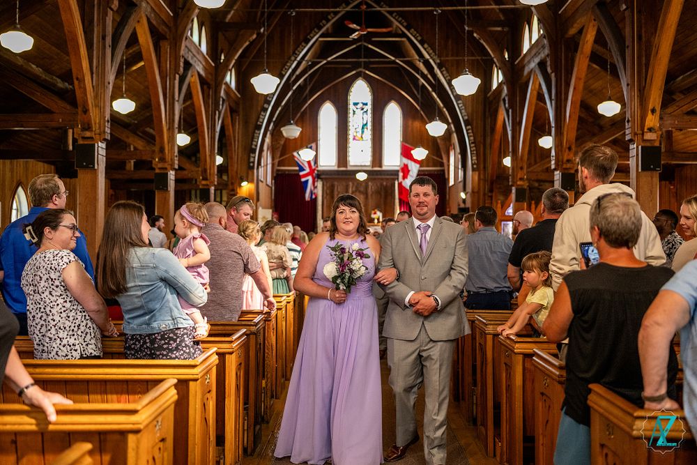 Wedding ceremony procession in historic church with wooden architecture and stained glass windows.