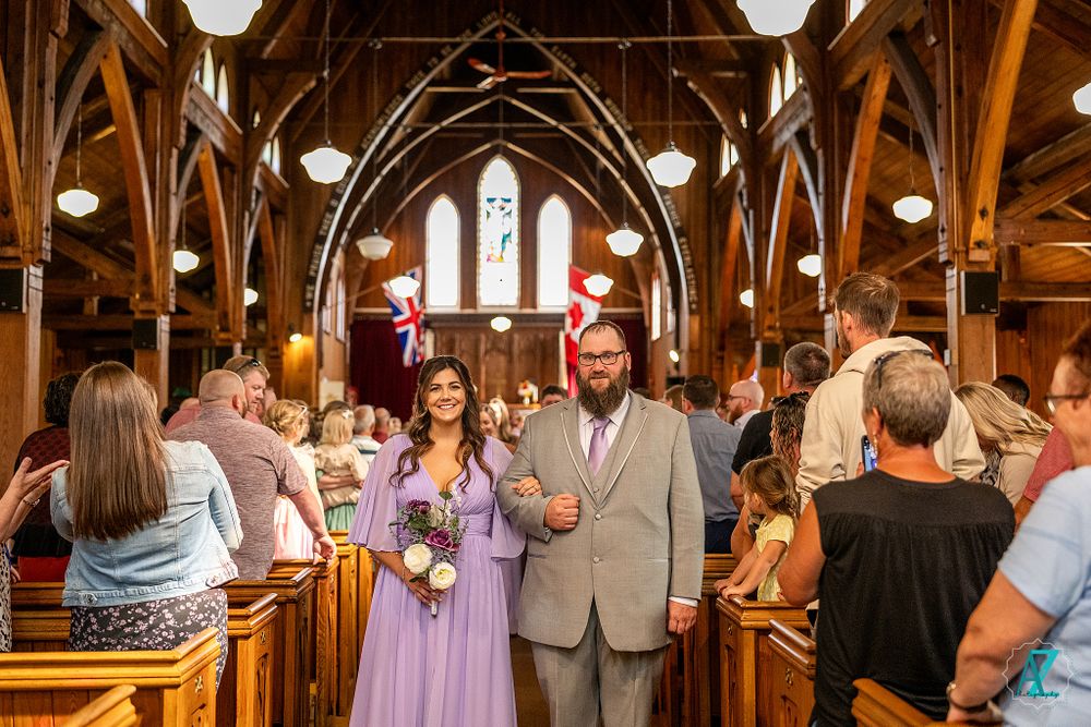 Wedding celebration inside gothic revival church with wooden beam ceiling and pendant lighting.