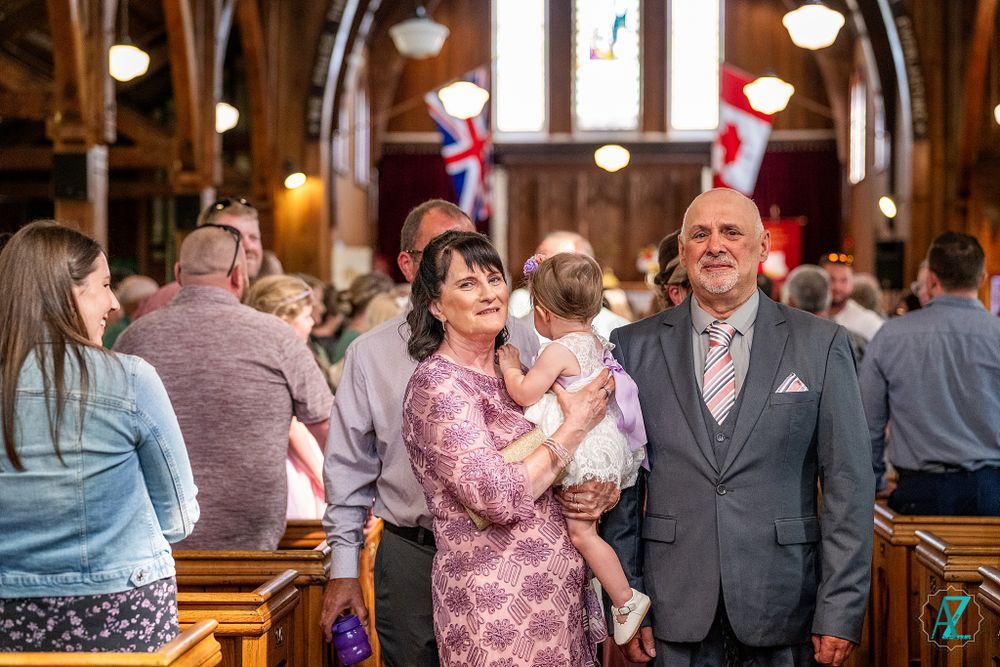 Wedding ceremony taking place in a beautiful historic church with wooden arches and decorative British flags.