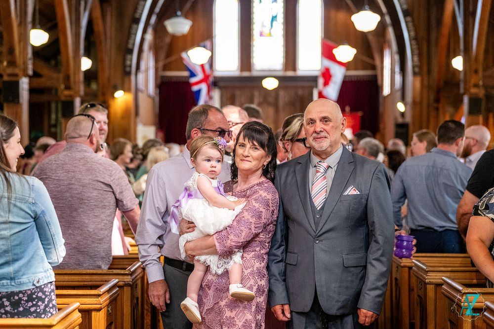 Family gathered during a christening ceremony inside an ornate church with traditional architecture.