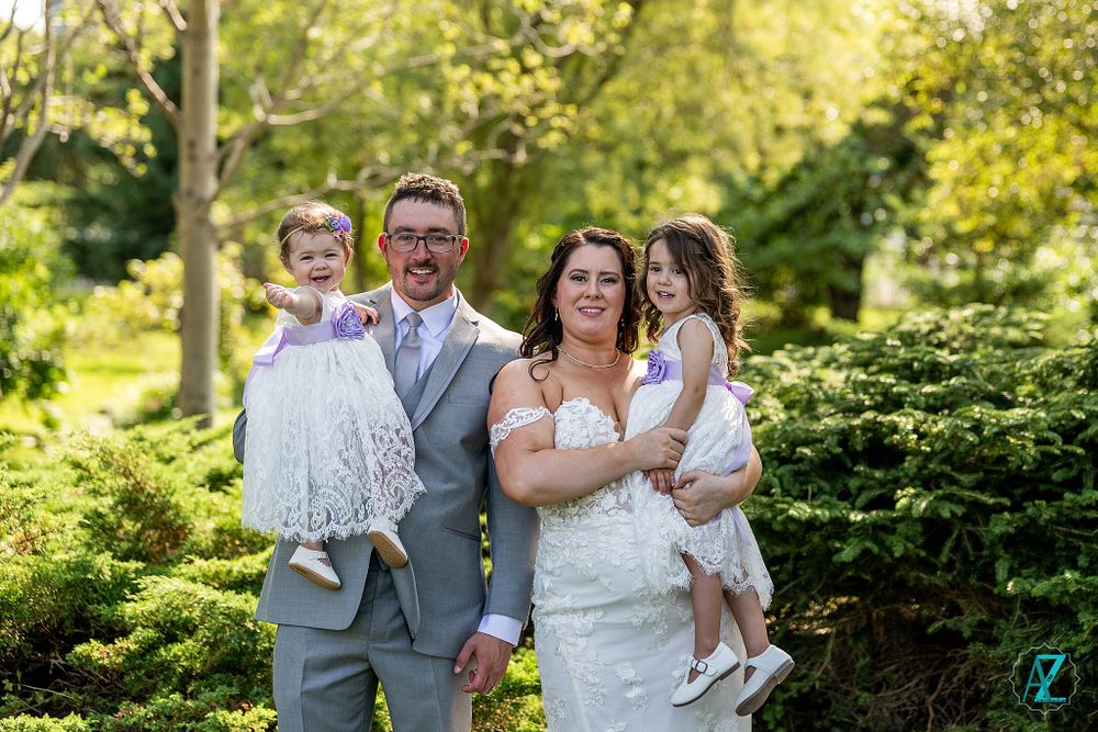 Wedding party poses together in a lush garden setting during spring or summer.