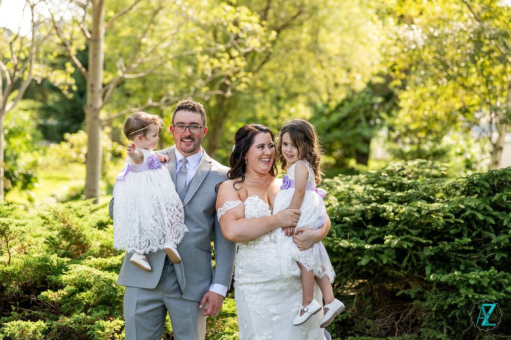 Sunny outdoor wedding portrait with natural greenery and trees in background.