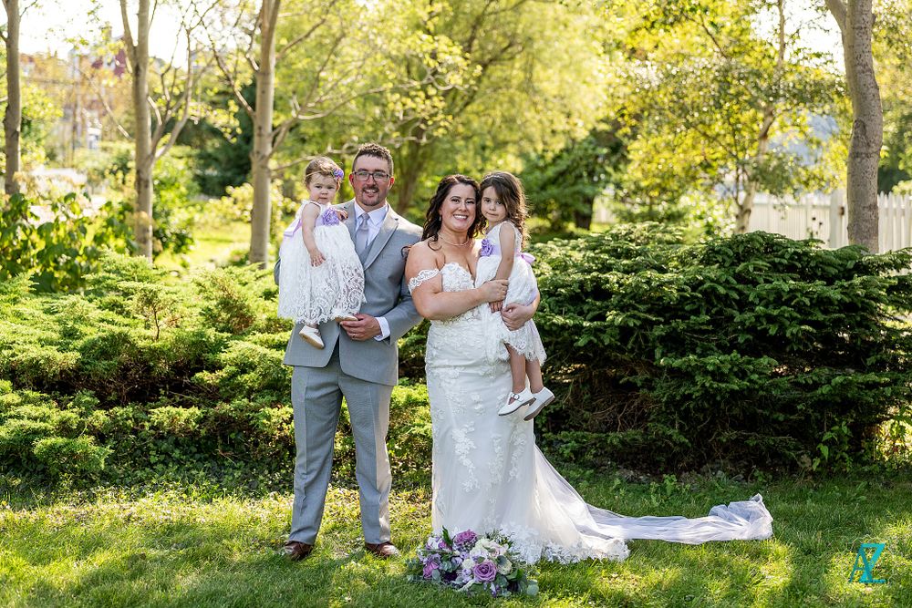 Wedding party poses in garden setting with beautiful natural lighting and landscaping.