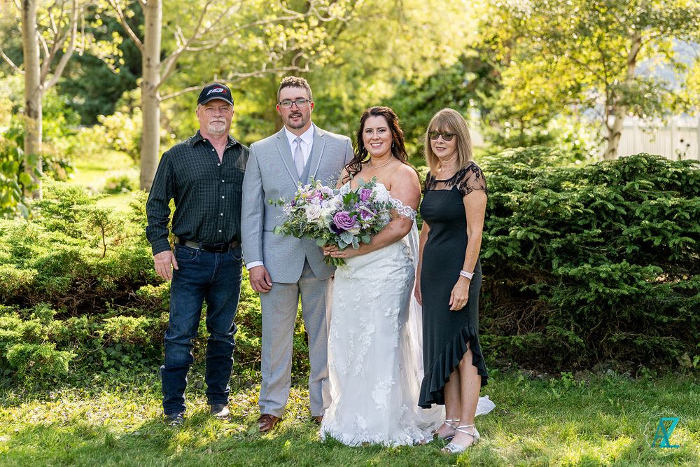 Wedding portrait in garden with mix of formal and casual attire.