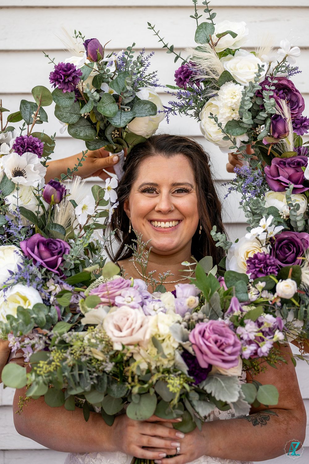 Beautiful floral arrangement with purple and white roses framing wedding portrait.