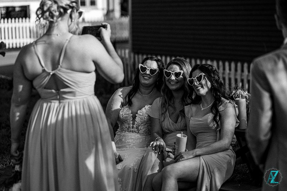 People in formal black and white dresses sit together wearing sunglasses.