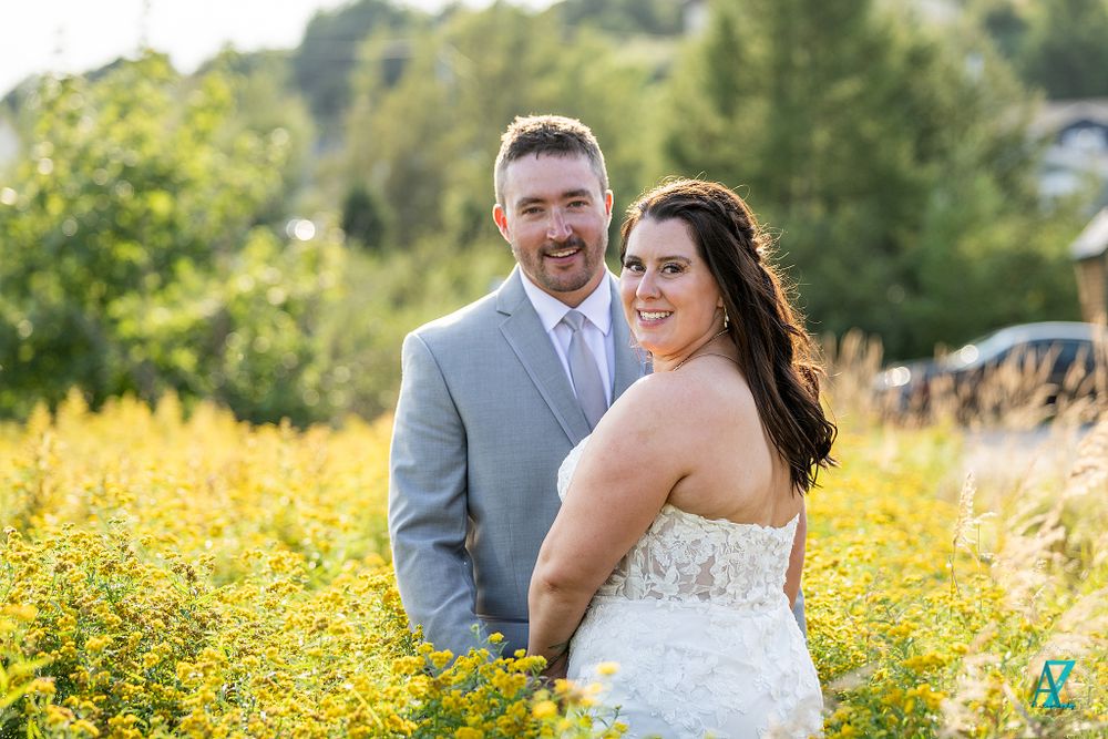 Joyful newlyweds pose together in a field of yellow wildflowers on their wedding day.