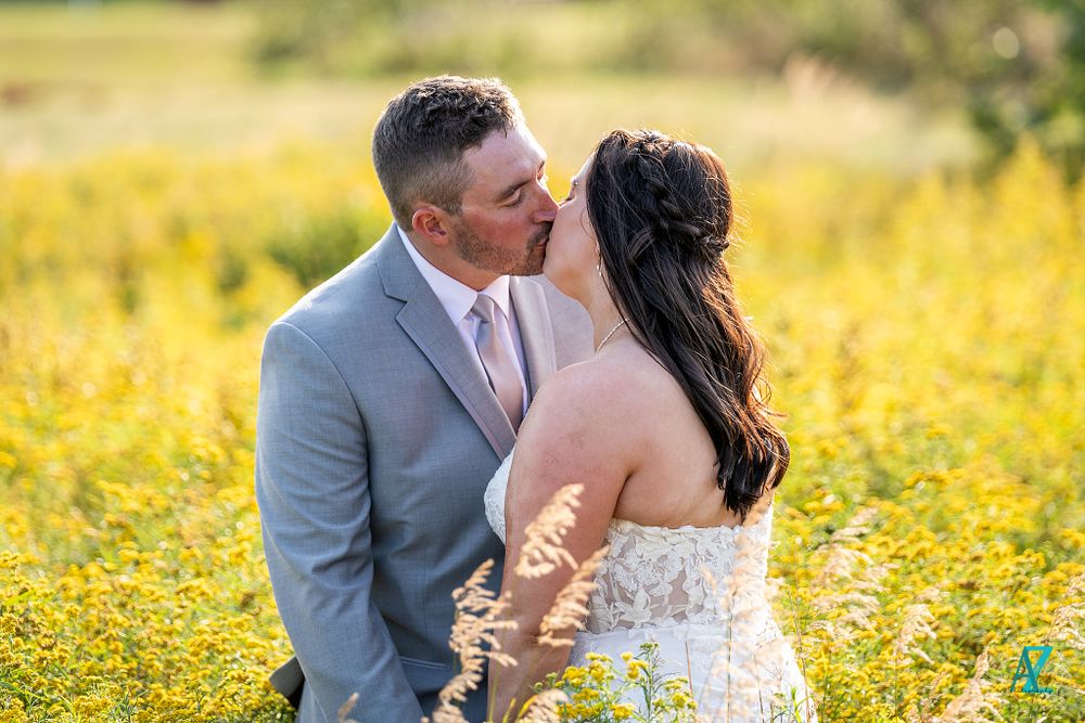 A romantic wedding couple embraces in a field of yellow wildflowers on their special day.