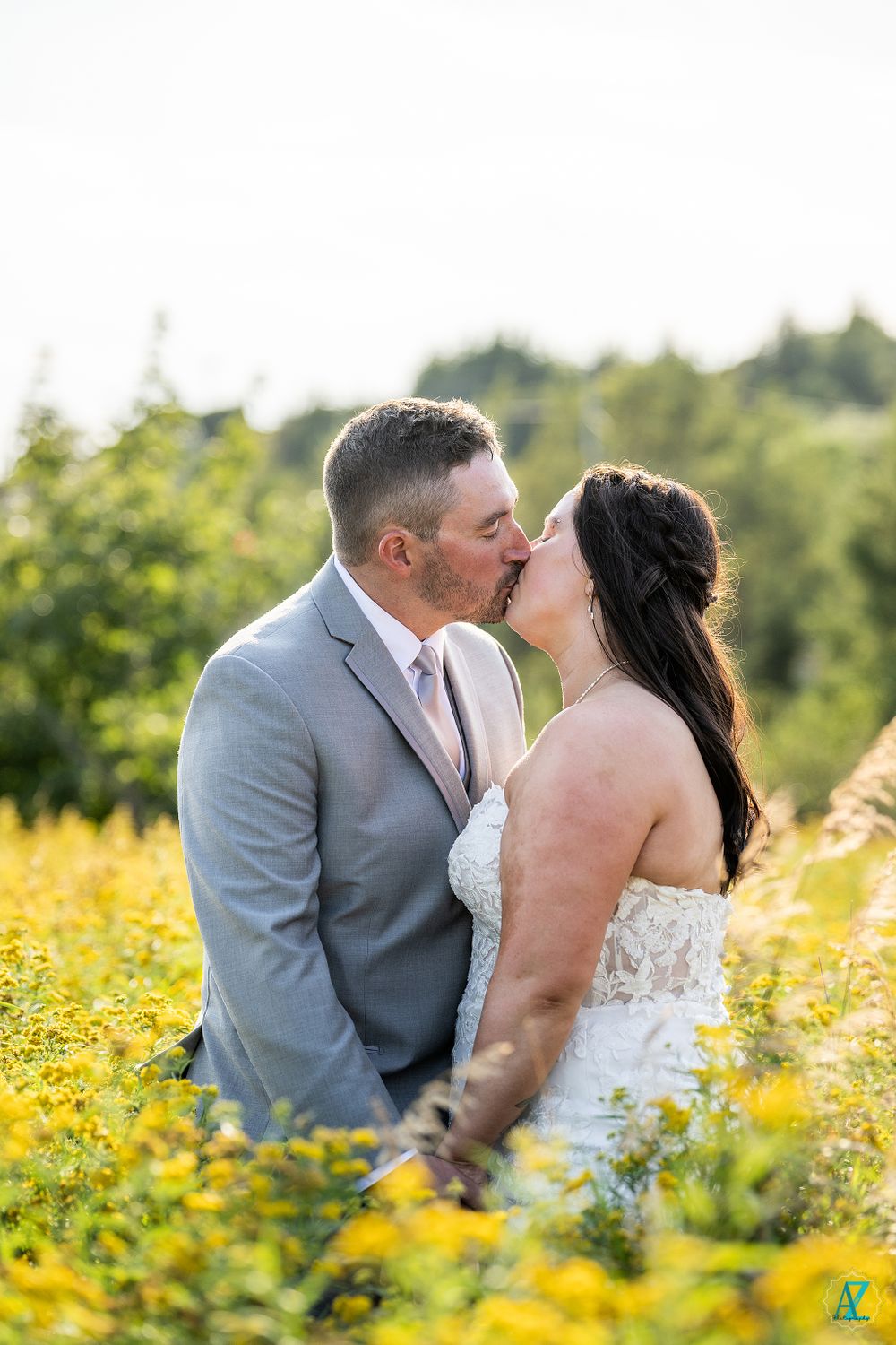 Newlyweds share a tender kiss surrounded by golden wildflowers on a sunny afternoon.