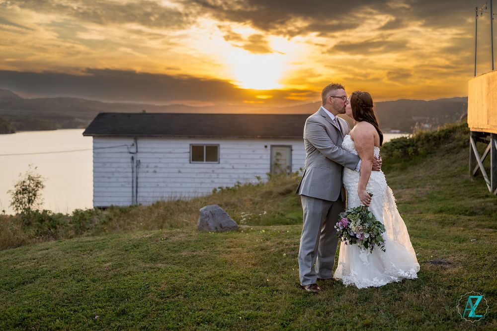 Romantic sunset wedding portrait against mountain backdrop with white building in background.
