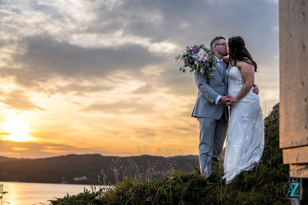 Romantic sunset wedding portrait against coastal landscape with dramatic sky.