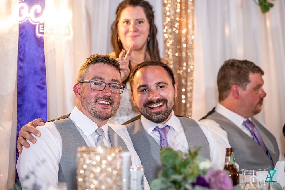 Wedding party members share laughter at the decorated reception head table.