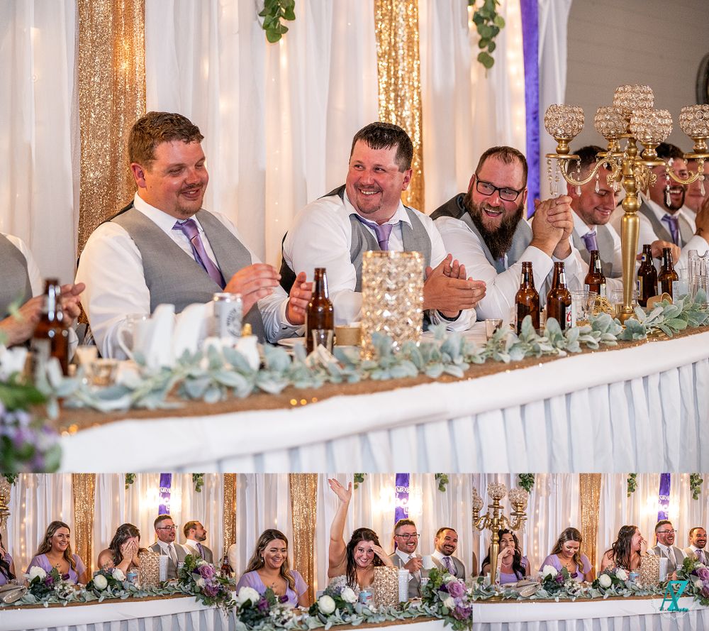 Wedding party seated at decorated head table with elegant centerpieces and champagne glasses.