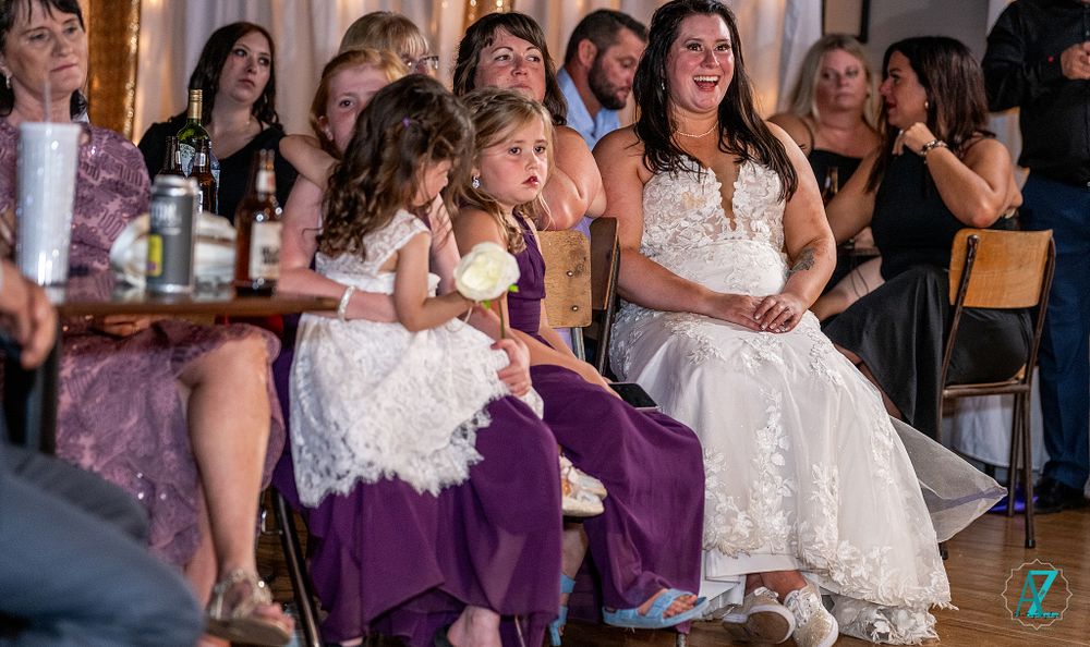 Wedding reception scene with guests seated in purple and white decor.