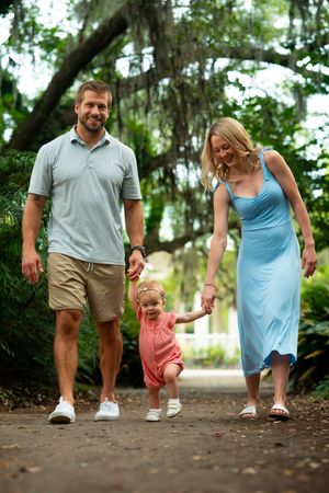 Family walking together on a shaded dirt path through lush greenery.