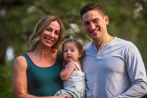 Family walking together on a wooded path during an outdoor photo session.