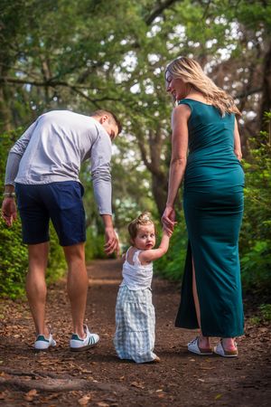 Family members walking together on a forest trail during golden hour.
