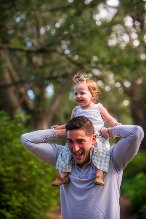 Playful moment captured between family members in a wooded setting.