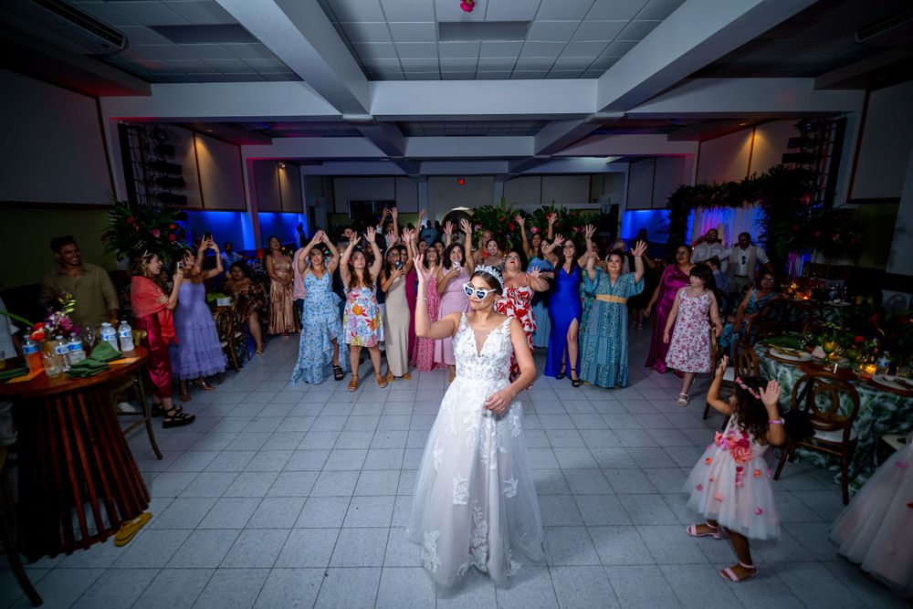 Wedding guests gathered at an indoor reception with colorful lighting and festive atmosphere.