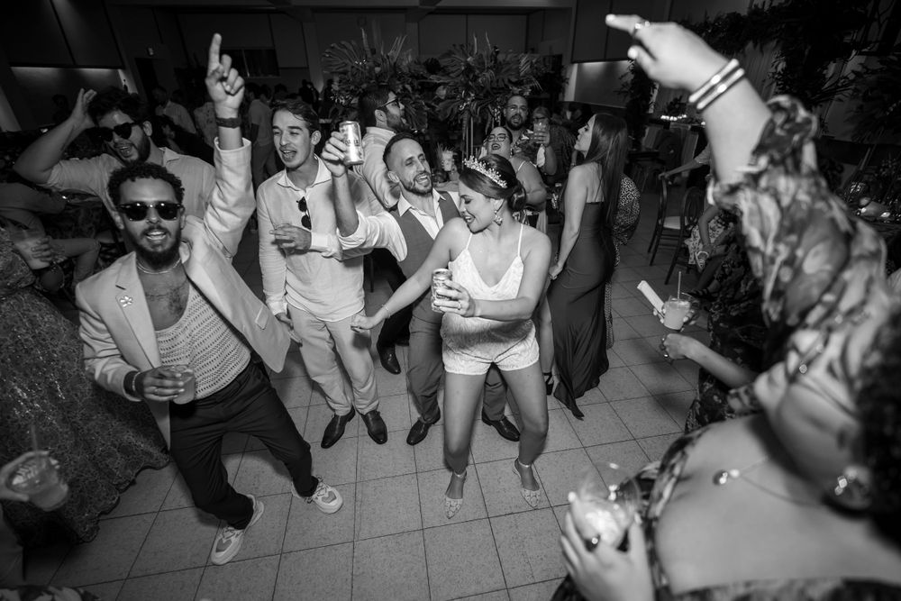 A lively black and white photo of wedding guests dancing and celebrating on the dance floor.