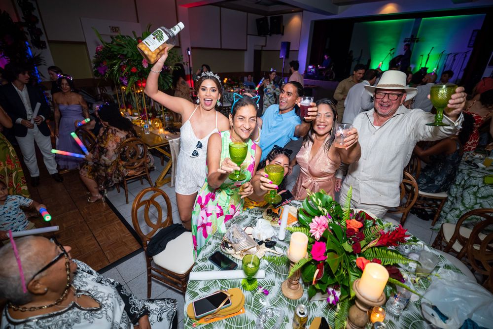 Group of celebrants cheering at a decorated dinner table with floral centerpieces.