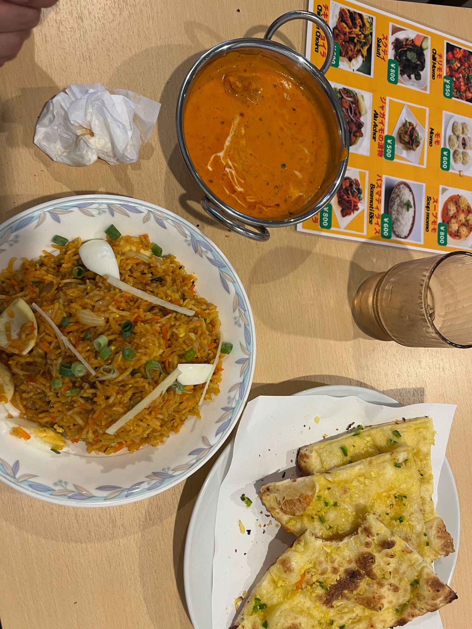 Indian curry dishes and naan bread served on white plates.