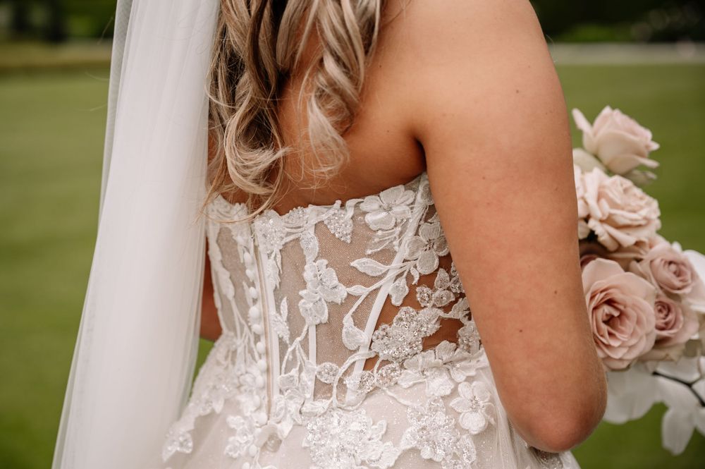 Close-up detail of intricate lace wedding dress bodice with floral appliques.