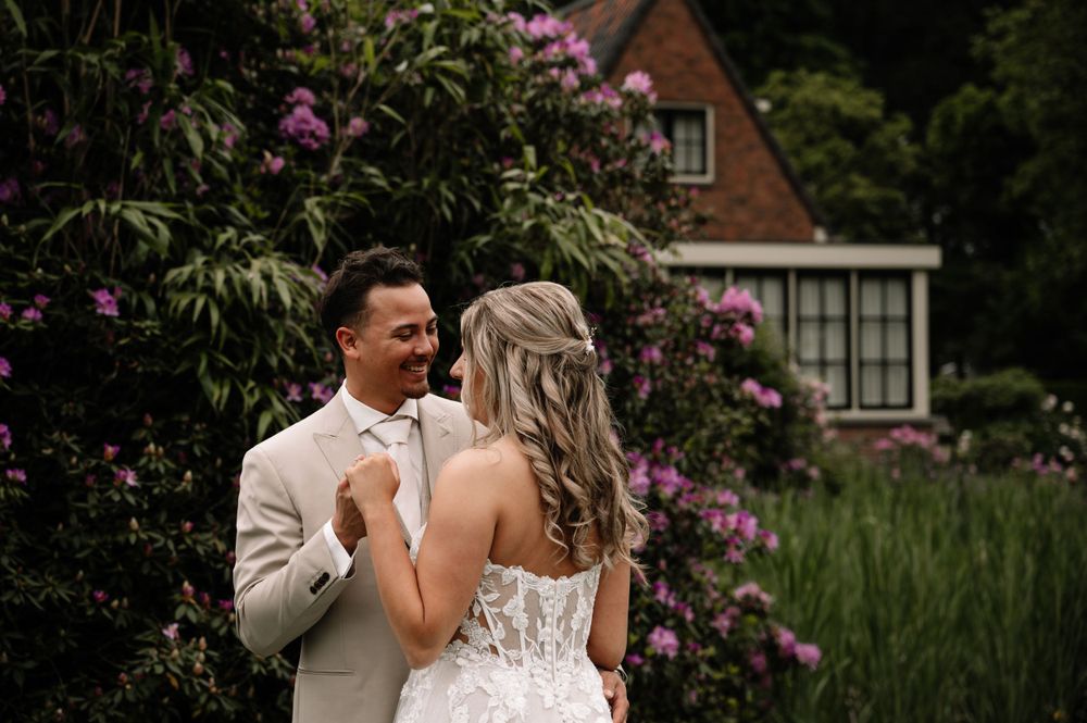 Wedding couple shares intimate moment among blooming garden flowers.