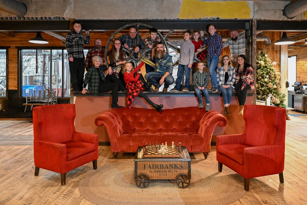 Large festive family group posing playfully around red velvet chairs with a Fairbanks table centerpiece.