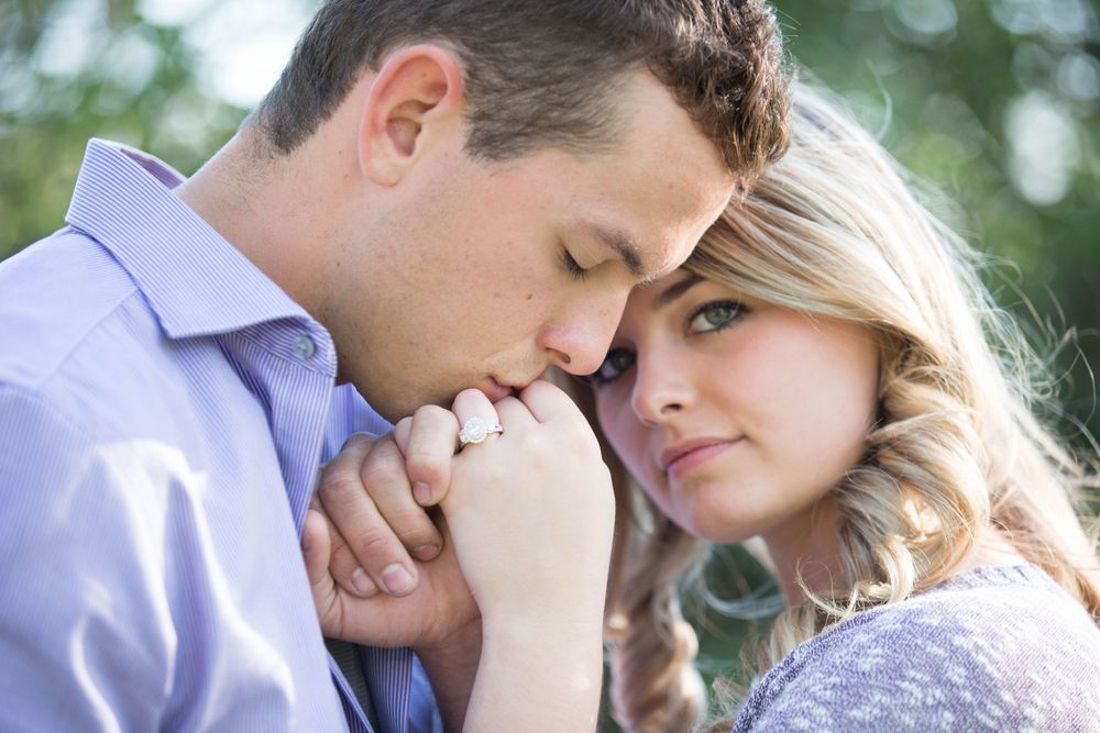 An intimate moment between a couple is captured in golden afternoon light among trees.