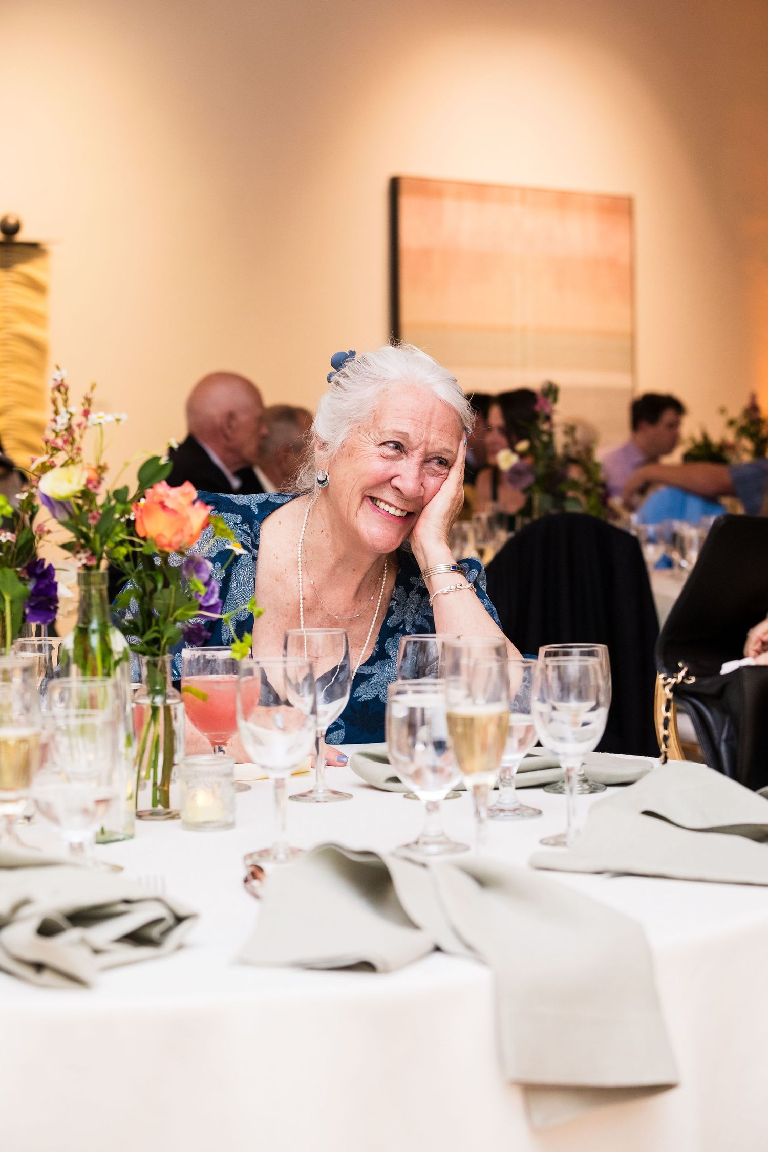 Wedding reception table where a guest is smile about her conversation with another guest not pictured.