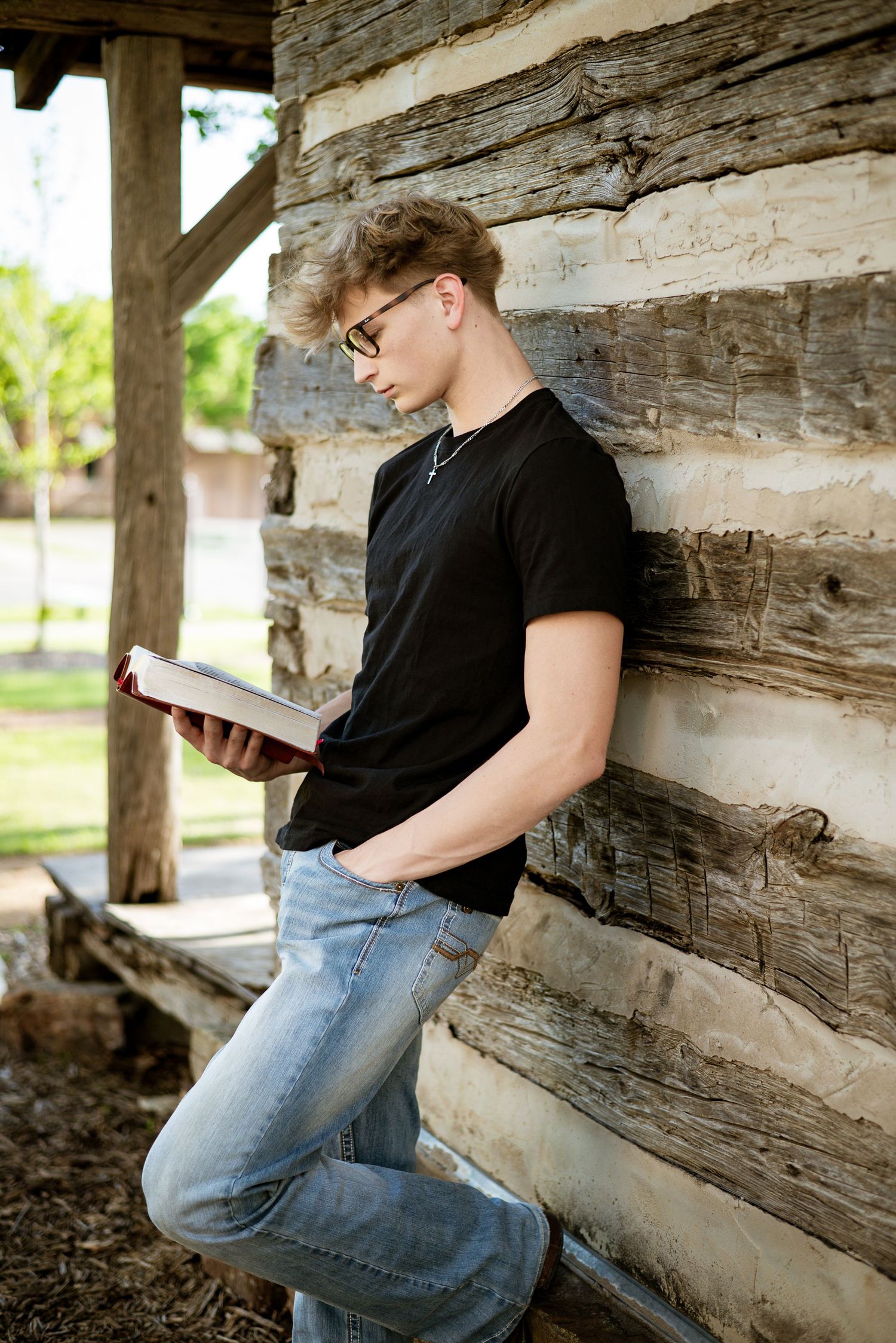 Casual portrait of reader against rustic log cabin wall.