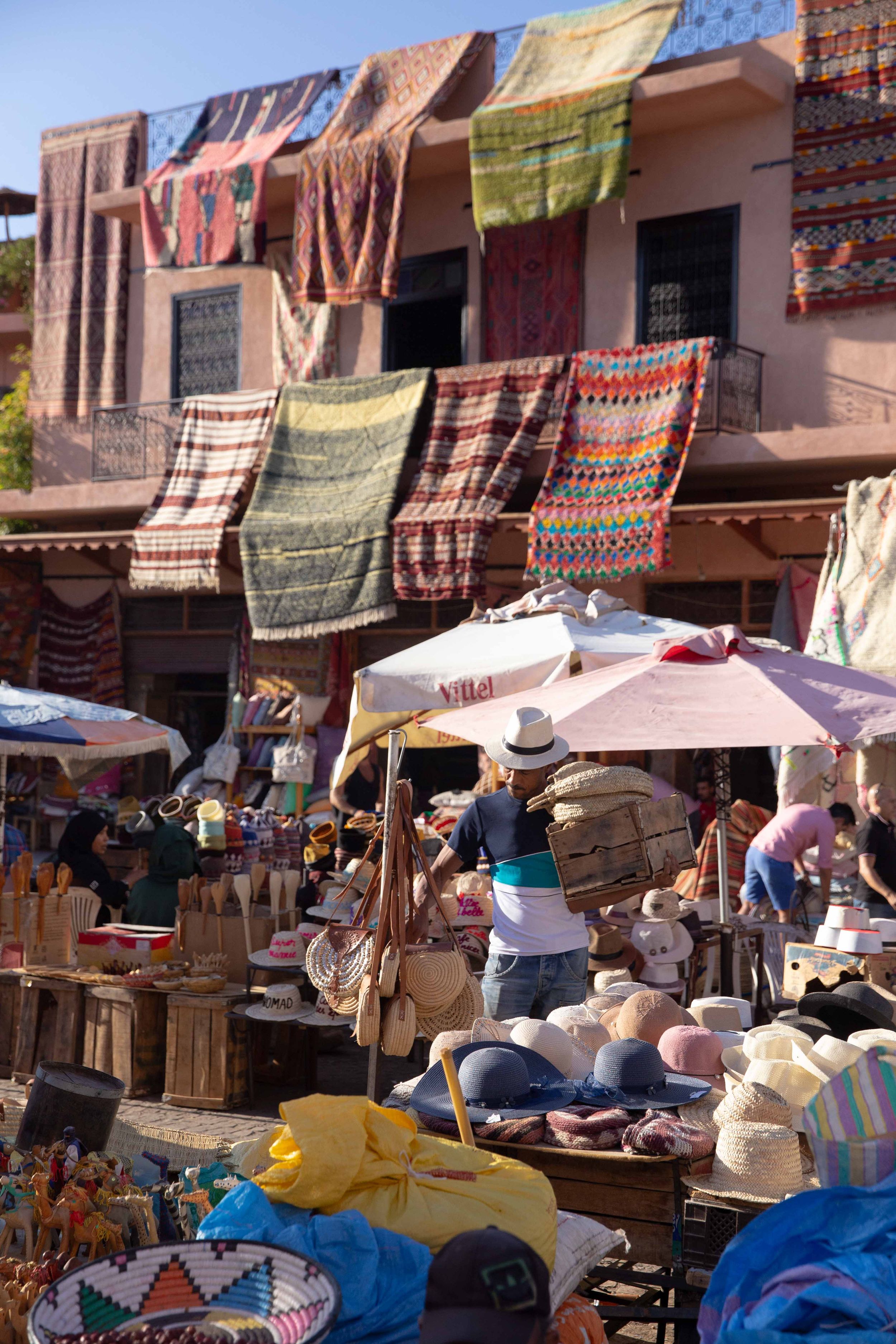 Colorful textiles and merchandise displayed at outdoor market stalls in Morocco.