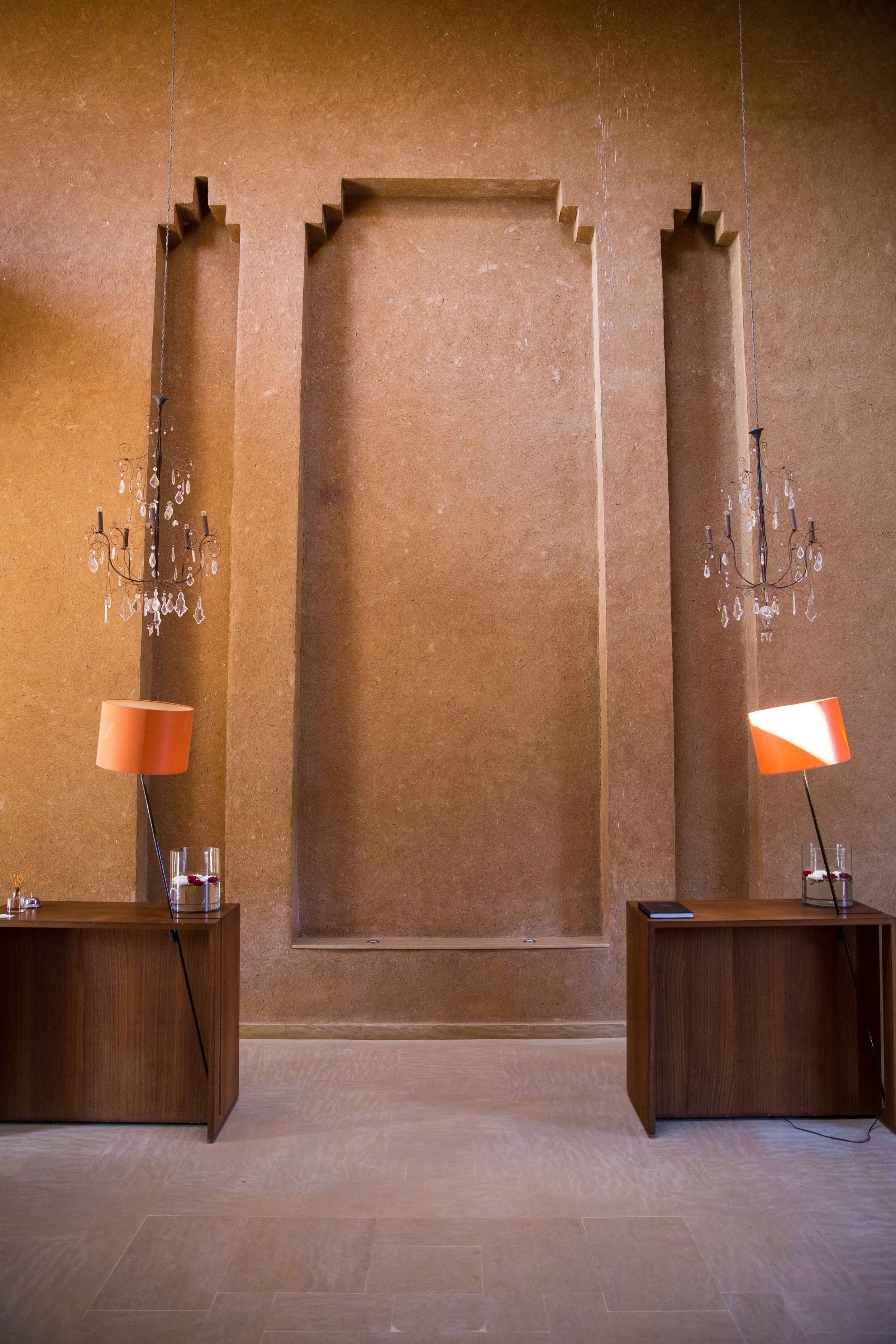 Symmetrical interior design with two modern table lamps and chandeliers against a beige wall.