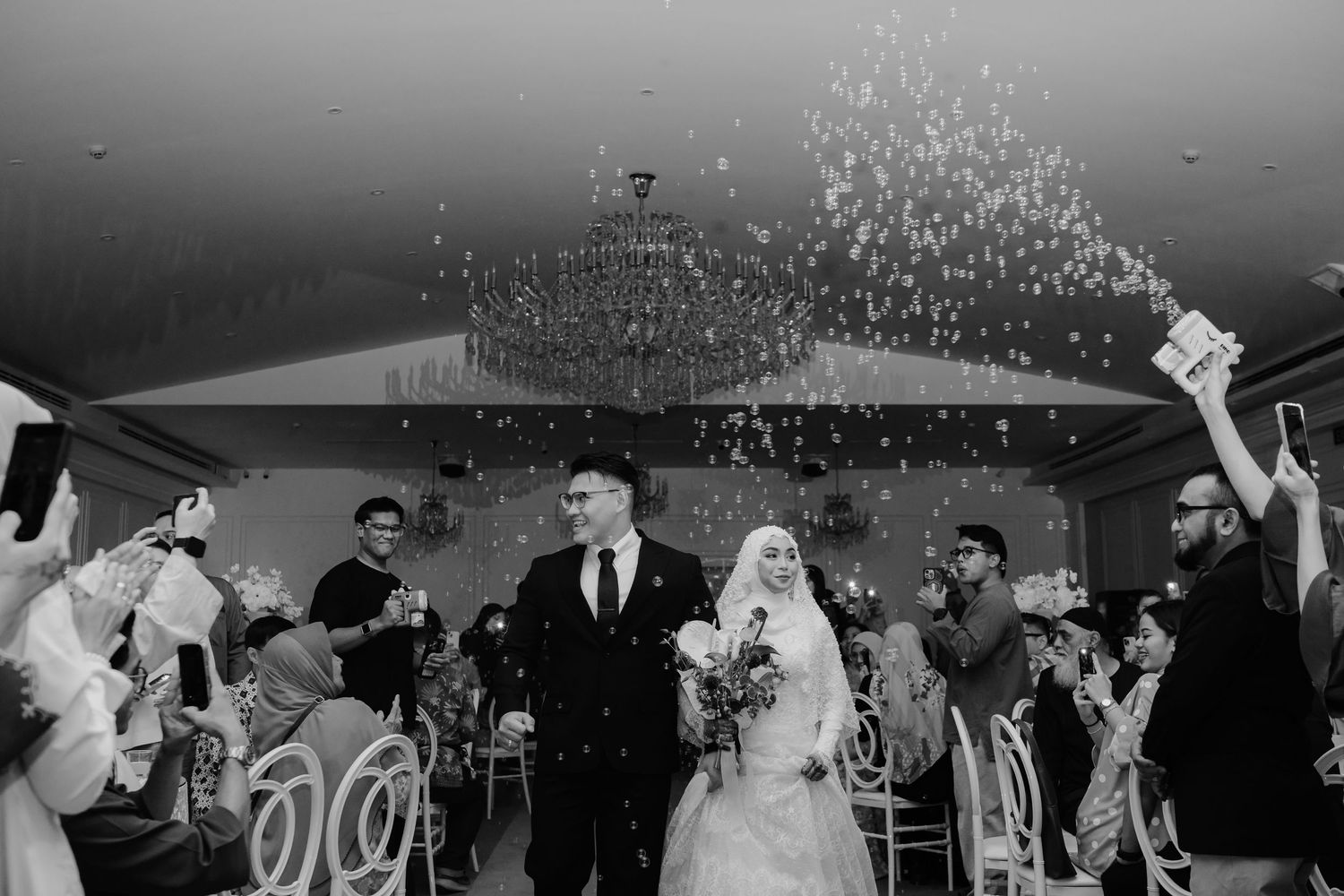 Wedding scene with floral decorations and white backdrop.