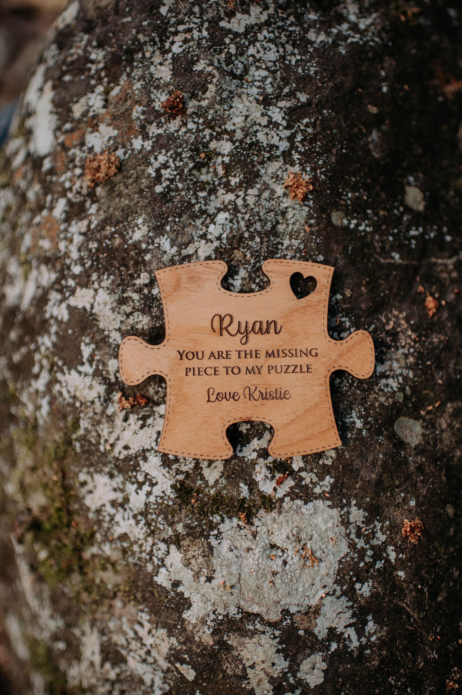 Wooden puzzle piece with romantic message engraved on rustic textured surface.