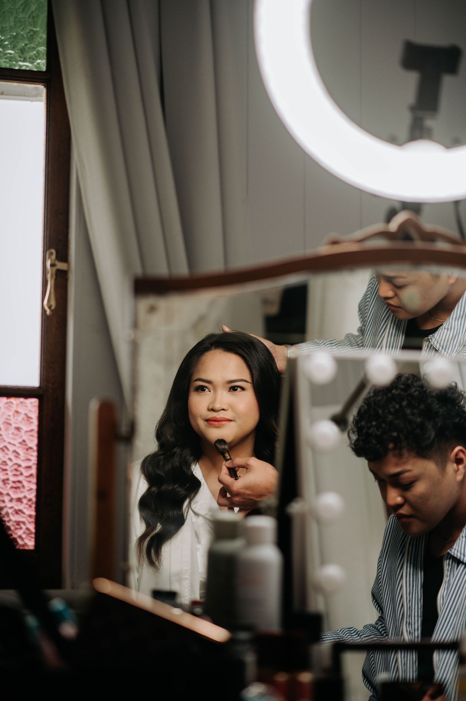 Getting ready scene with a ring light and makeup application in progress.