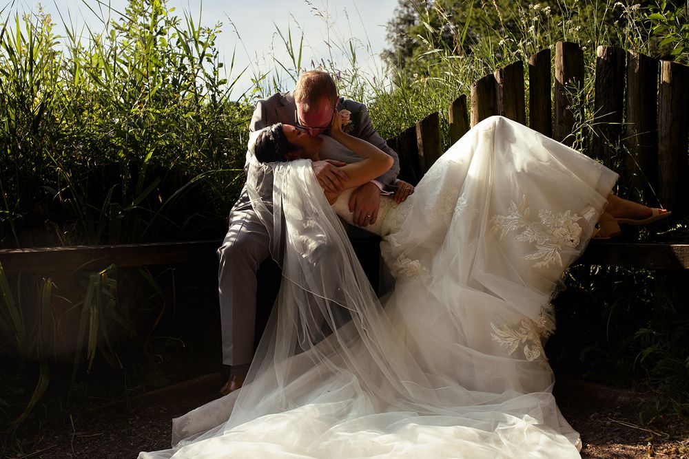 Groom dips bride in white lace wedding gown and veil outdoors at Brockholes Nature reserve. Jane Ball Photography