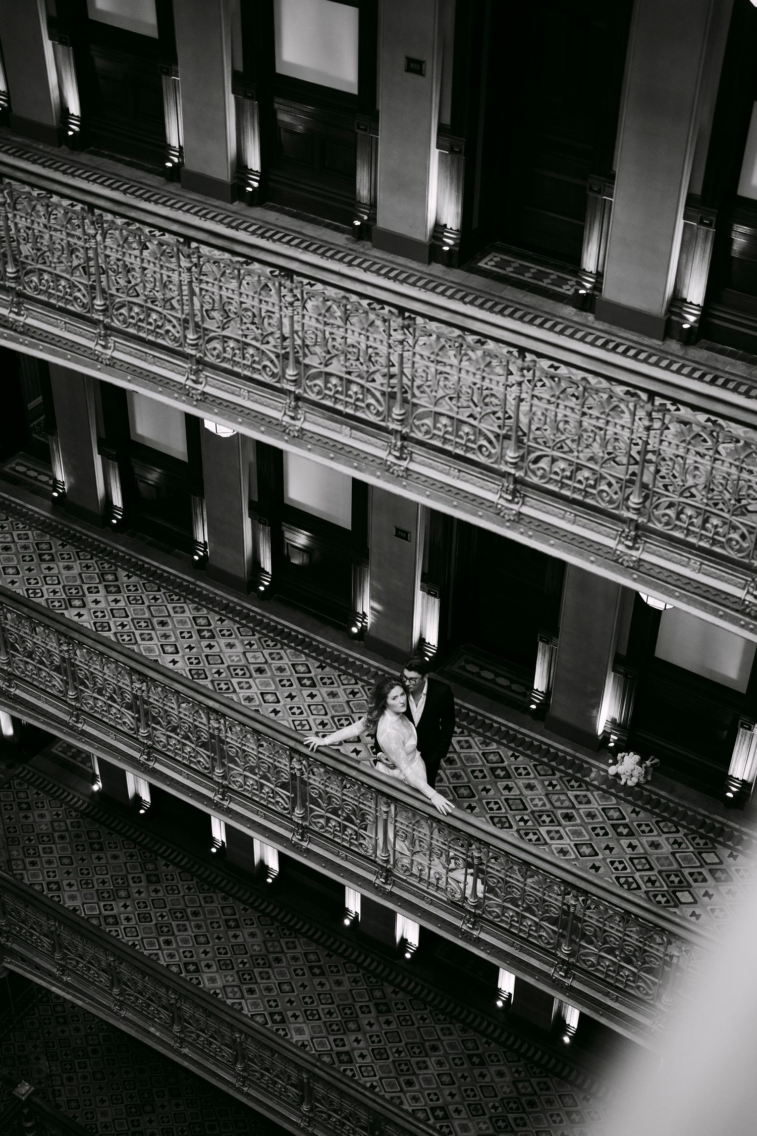 Dramatic black and white view of ornate theater balcony seating and architectural details.