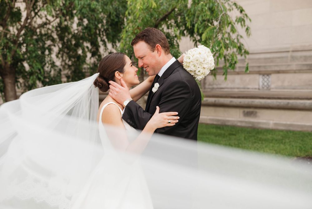 Wedding couple shares romantic kiss against classic stone architecture.