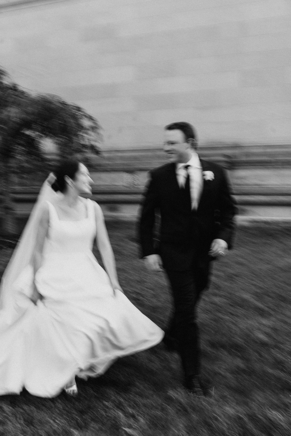 Black and white sequence of a couple running playfully through a grassy field.