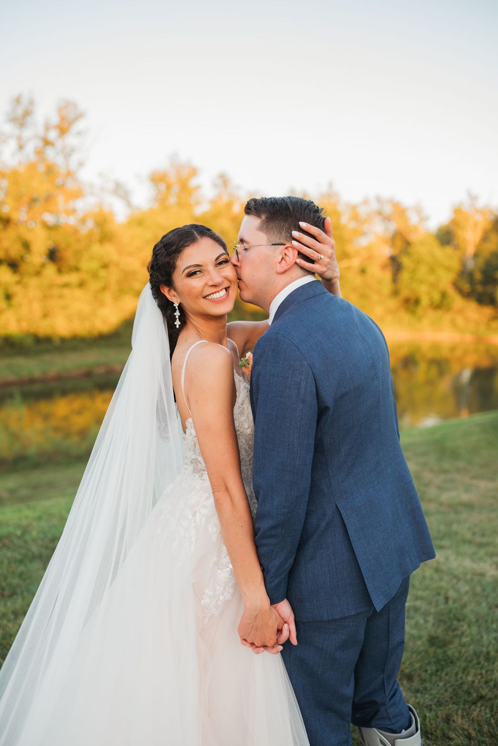 A romantic wedding couple shares an intimate moment at sunset in an outdoor setting.