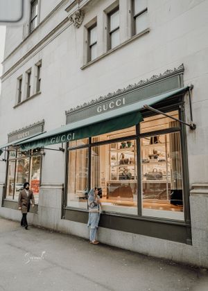 Exterior view of Gucci store with illuminated display windows and classic storefront design.