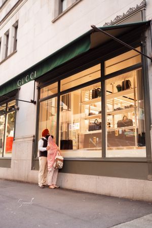 Two people window shopping outside a brightly lit Gucci storefront.