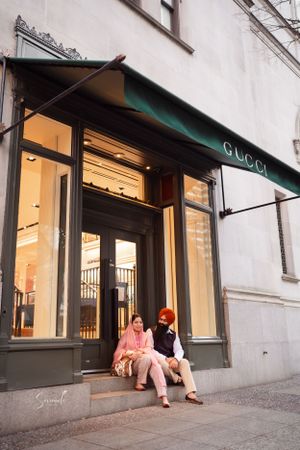 Couple sitting on steps outside a Gucci store entrance.