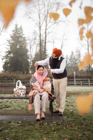 Casual autumn park scene with couple sharing a tender moment on wooden bench.