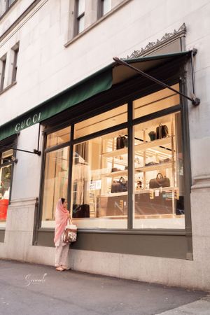 Person looking at luxury handbags displayed in a Gucci store window.
