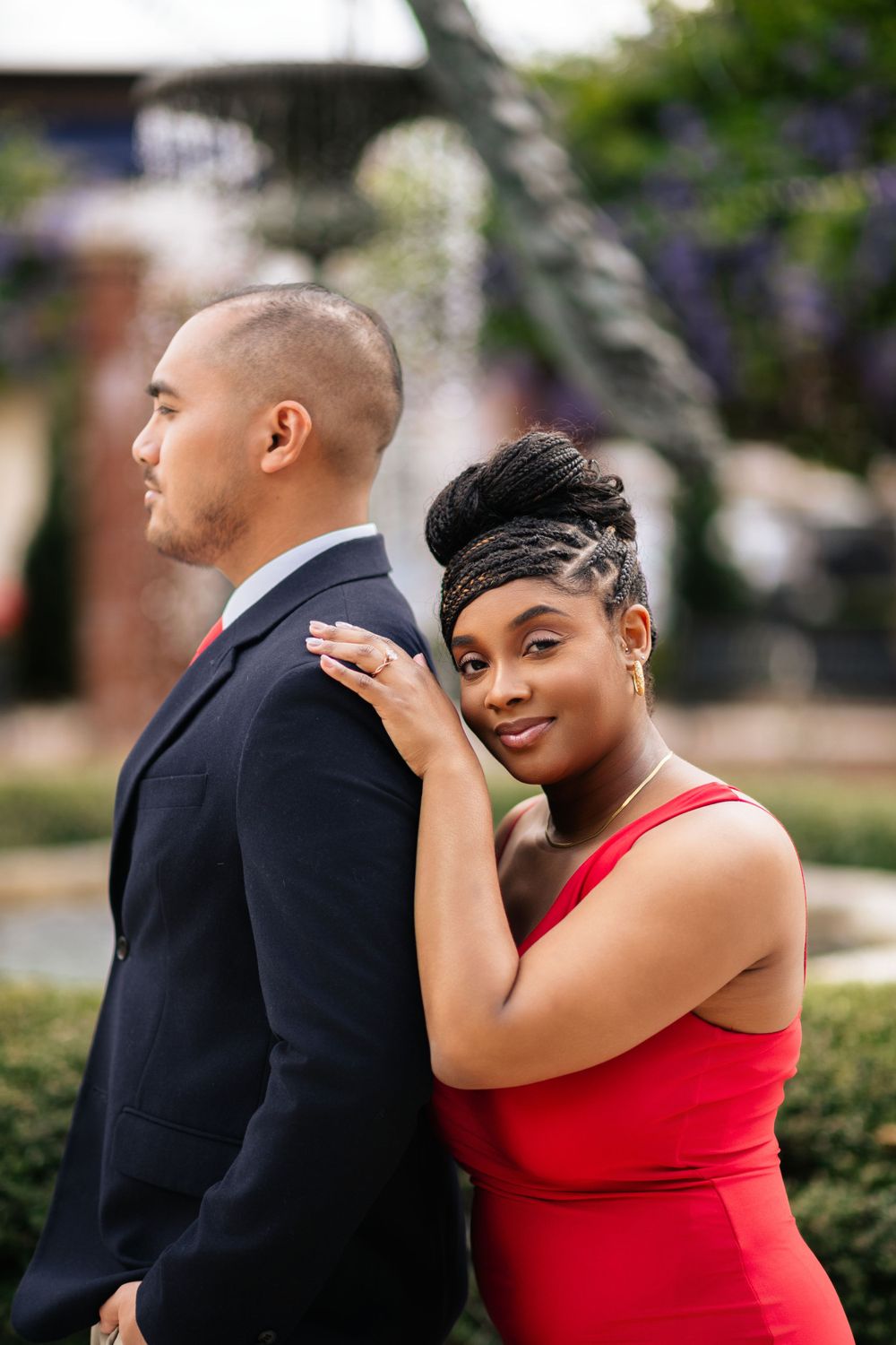 Elegant couple in formal attire posing for portrait in garden setting.