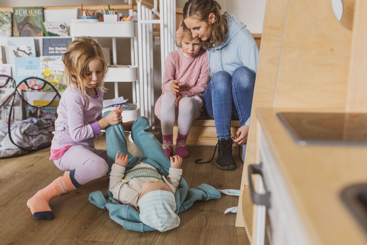 Foto vom Herumtoben der Kinder mit dem Papa, zu Hause im Wohnzimmer der Familie, aufgenommen bei einer Familienreportage.
